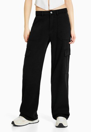 Black cargo pants made of cotton with a relaxed fit. Features include large side pockets, a high waist, and a silver button closure.