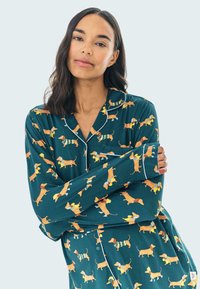 Conjunto de pijama de manga larga en tejido color teal con un divertido estampado de dachshund. Detalles en blanco en el cuello y las mangas. Textura suave y ligera.