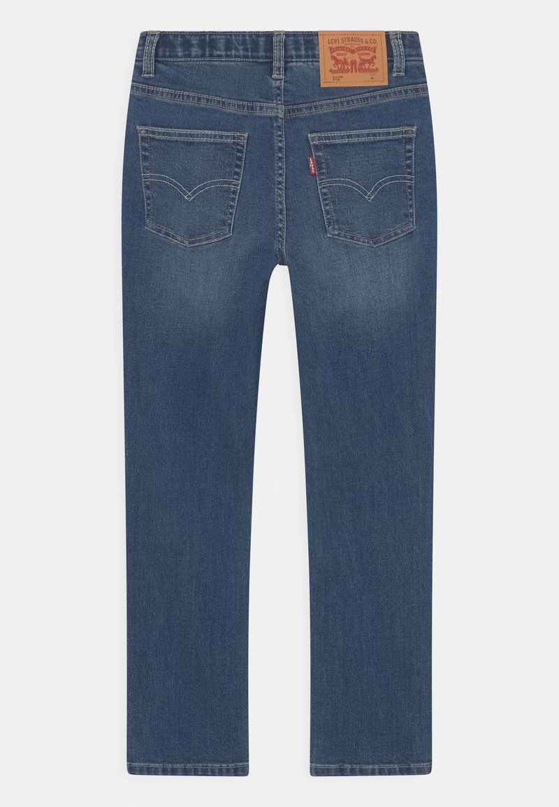 Jeans en denim bleu avec une coupe droite, dotés de deux poches arrière et d'un patch en cuir à la taille. Fini vieilli visible.
