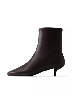 Bottine en cuir marron foncé avec bout pointu et petit talon kitten, vue de profil sur fond blanc.