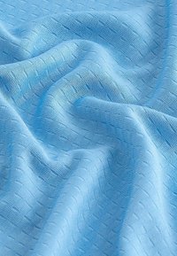 Hellblaues, strukturiertes Gewebe mit einem weichen, gewebten Muster. Die Oberfläche zeigt subtile Linien und Wellen, die ein glattes Aussehen erzeugen.