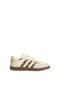 Beżowo-białe buty sportowe Adidas z beżowo-czarnymi paskami w panterkę, gumową podeszwą i wiązaniem na sznurowadła, pokazane z boku na białym tle.
