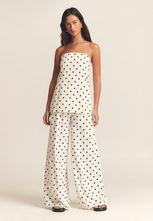 White strapless top and wide-leg trousers featuring a black polka dot pattern. Soft fabric with a loose fit and minimalistic design.
