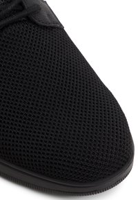 Czarne buty sportowe z chropowatą siateczką, zaokrąglonym czubkiem i gumową podeszwą. Charakteryzują się minimalistycznym wzornictwem i sznurowaniem.