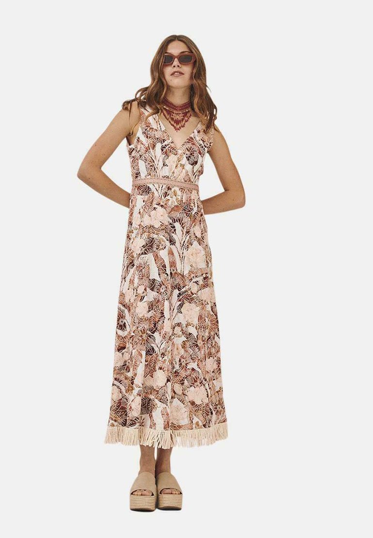 Vestido largo con estampado floral en tonos de rosa y marrón. Presenta un escote en V, cintura ajustada y dobladillo con flecos. Combinado con zapatos de plataforma.