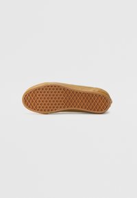 Sole of a sneaker with a textured, diamond-pattern brown rubber bottom. The edge is rounded, transitioning to a flat side.