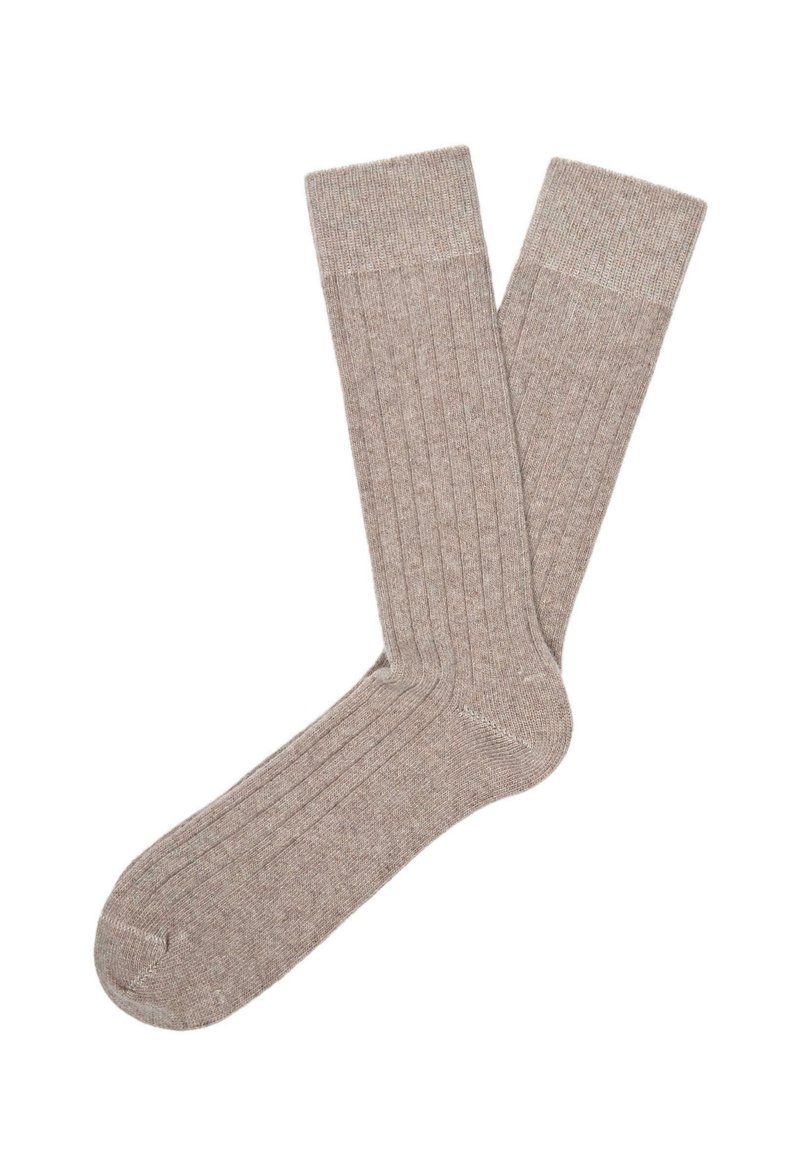 Calzini beige a coste realizzati in un materiale morbido, con tallone e punta rinforzati, una superficie liscia e leggere variazioni di colore.