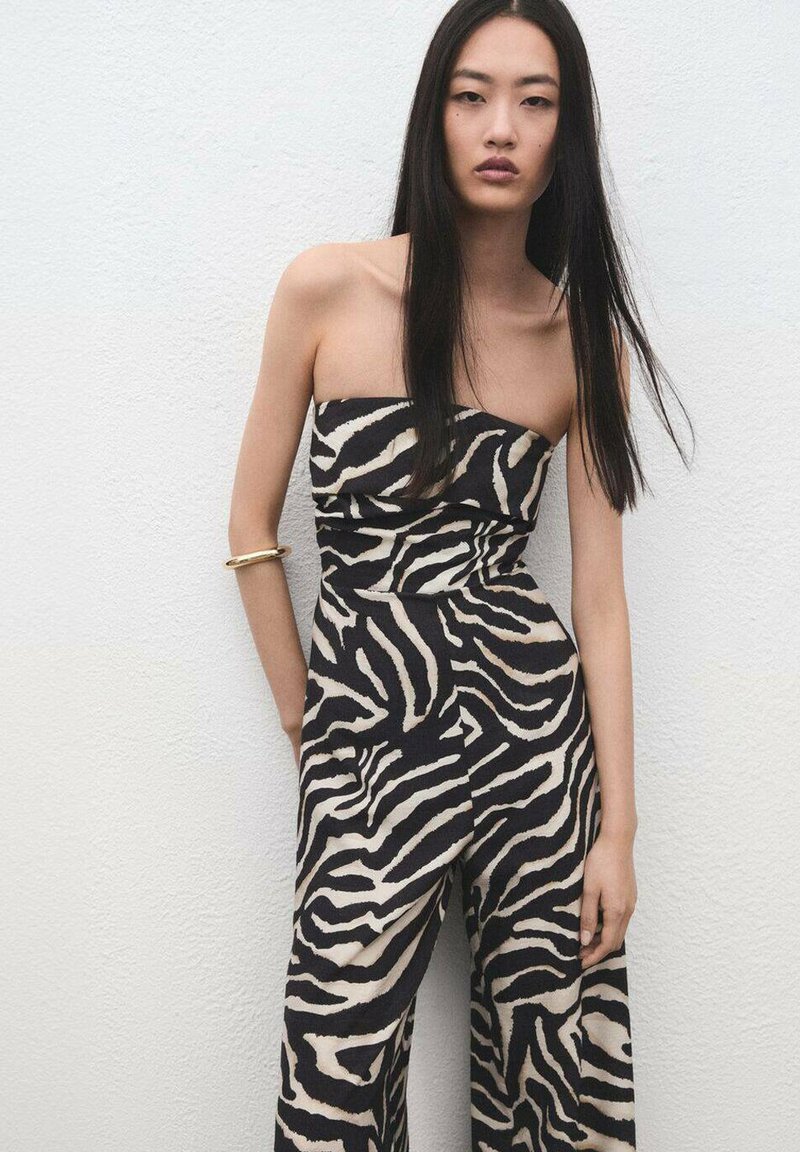 Mono sin tirantes en negro y beige con rayas de cebra, que presenta un corsé ajustado y pantalones de pierna ancha, textura suave y detalles mínimos.