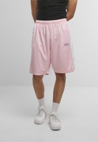Shorts de sport roses avec des rayures blanches sur les côtés, une taille élastique et un petit logo sur le devant. Fabriqué en matériau léger et respirant.