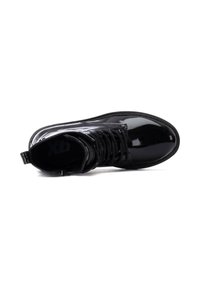 Botas de tobillo de charol negro con cierre de cordones, punta redonda y suela texturizada. Incluye una pestaña para facilitar el uso.