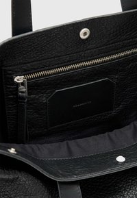 Zwarte leren totebag met een textuurrijke buitenkant, binnenvak met ritssluiting en een zachte stoffen voering. Subtiele metalen hardware accenten.