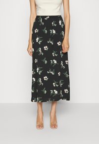 Jupe midi noire à motif floral avec une coupe décontractée, présentant des fleurs blanches et roses ainsi que des feuilles vertes, fabriquée en tissu doux et léger.