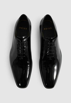 Schwarze, polierte Leder-Schnürschuhe mit einem spitzen Zehen-Design. Verfügt über eine glatte Oberfläche und ein goldenes Logo auf der Innensohle.