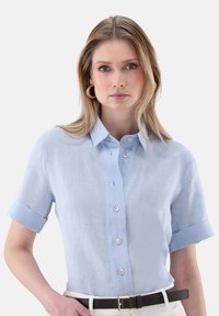 Light blue short-sleeve blouse made of linen, featuring a button-down front, folded cuffs, and a relaxed fit.