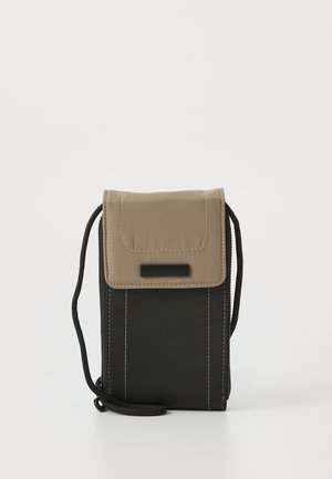 Textured pouch in black fabric with a tan flap and black accents. Features a shoulder strap and stitching details along the sides. Zipper closure.
