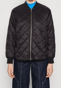 Schwarze, gesteppte Bomberjacke mit einem Frontreißverschluss, gerippten Bündchen und einer glatten Textur. Mit einem Rautenmuster in der Steppung.
