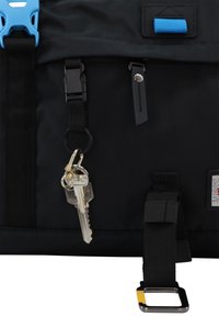 Black fabric bag with a blue buckle, keychain, zipper pull, and detailed texture. Features adjustable straps and a silver hardware accent.