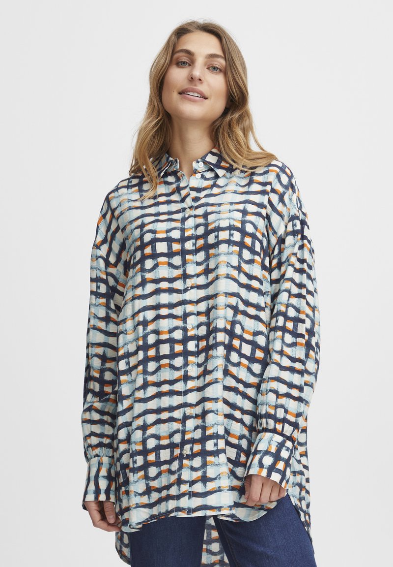 Camisa abotonada con un patrón de cuadrícula en azul, blanco y naranja. Mangas largas, corte relajado y dobladillo curvado. Tejido ligero y superficie texturizada.