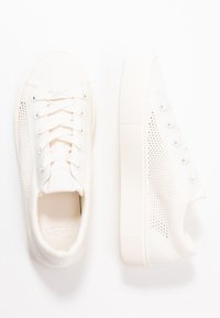 Białe sneakersy z teksturowaną siateczkową cholewką i solidną gumową podeszwą. W wyposażeniu okrągłe sznurowadła i minimalne logo na języku.