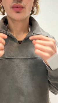 Šedý fleecový pulovr s čtvrtčtvercovým zapínáním, který má žebrovanou texturu a výstřih ve stylu henley, doplněný hnědou vnitřní vrstvou.