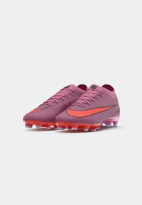 Un paio di scarpini da calcio Nike di colore rosa e arancione, con lacci, tacchetti stampati e grandi loghi Swoosh arancioni su uno sfondo bianco.