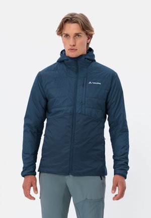 Giacca isolante blu navy con cappuccio, sezioni superiori trapuntate, tessuto liscio nella parte inferiore, tasca sul petto e zip anteriore. Design leggero e aderente.
