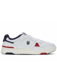 Białe sportowe sneakersy z granatowymi i czerwonymi akcentami, górna część z gładkiej skóry, sznurowany design, naszywka z logo z boku oraz teksturowana gumowa podeszwa.