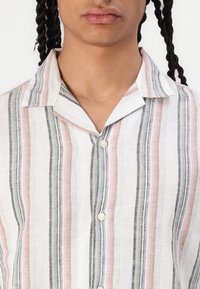 Striped button-up shirt featuring vertical stripes in shades of pink, gray, and white. Made of lightweight, textured fabric with a collar.