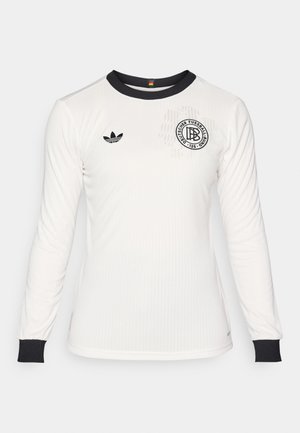 Camiseta de fútbol blanca de manga larga con textura acanalada, cuello y puños negros, que presenta un logo negro con texto y un emblema de adidas en el pecho.