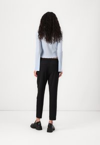 Lys blå ribbet langermet topp med bølget kant, kombinert med svarte, smale bukser og svarte plattform loafers.