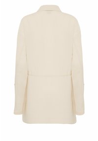 Beige übergroße Hemdjacke mit Kragen, langen Ärmeln und strukturiertem Stoff. Verfügt über senkrechte Nahtdetails und seitliche Schlitze für mehr Bewegungsfreiheit.