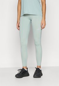 Svetlomodré legíny s hladkou textúrou a kontrastným prešitím. Logo Adidas je výrazne zobrazené v bielej farbe na stehne.