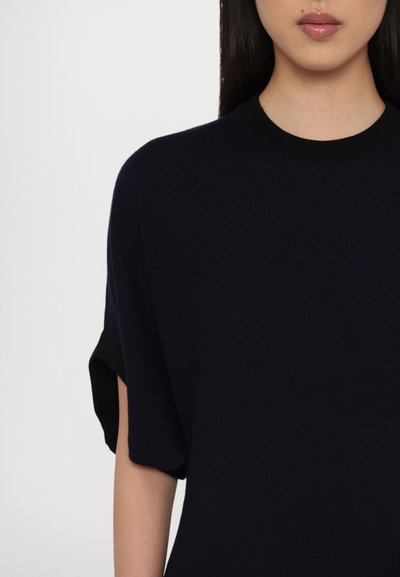 Pull bleu marine à manches courtes avec un col rond, présentant une texture lisse et des accents noirs contrastants sur les manches.
