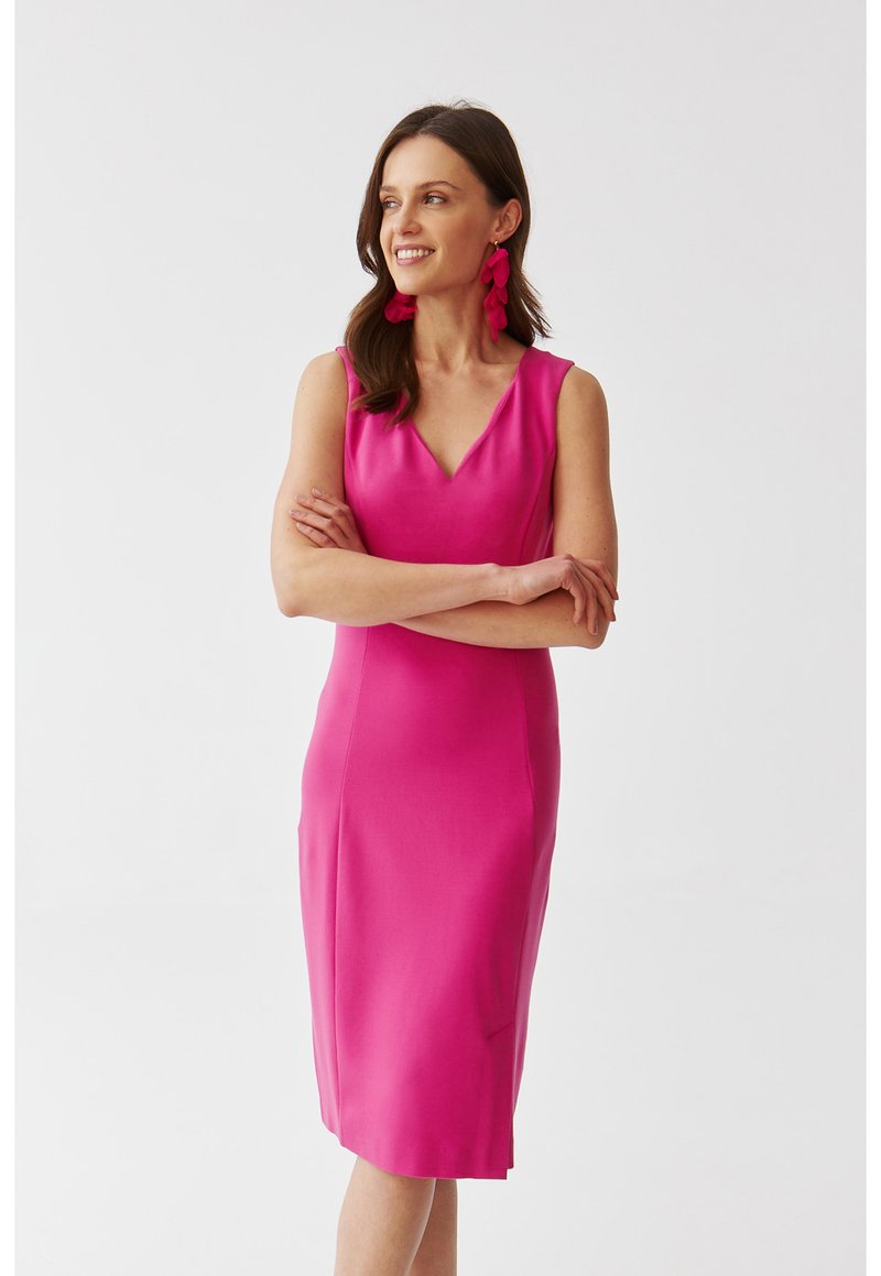 Kitsas roosa sleeveless kleit V-kujulise dekoltee, sile tekstuur, põlvepikkune lõige ja külje lõhikudetail. Rikkalikud roosad kõrvarõngad lisavad aktsenti.