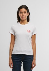 Witte katoenen T-shirt met korte mouwen, voorzien van een rood geborduurd logo op de linker borst. Rechte zoom en casual pasvorm.