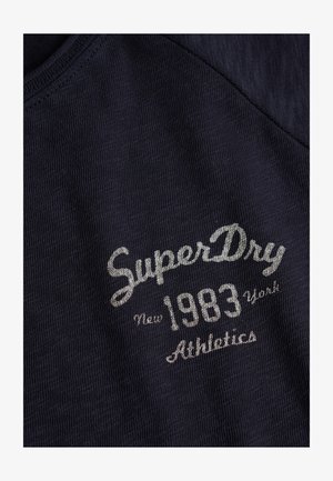 Granatowy bawełniany t-shirt o prążkowanej fakturze, z srebrnym haftowanym napisem: "SuperDry", "New 1983 York" oraz "Athletics" na przodzie.