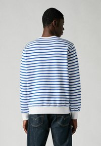 Langsleeve sweatshirt met ronde hals in blauw en wit horizontale strepen, gemaakt van zachte stof. Heeft geribbelde manchetten en zoom. Donkere jeans zichtbaar.