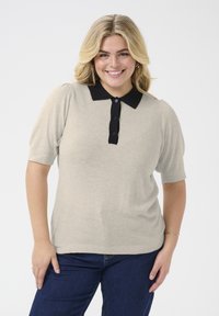 Bežna polo majica kratkih rukava s teksturiranom tkaninom, crnim rebrastim ovratnikom i dugmadi. U kombinaciji s tamnoplavim trapericama.