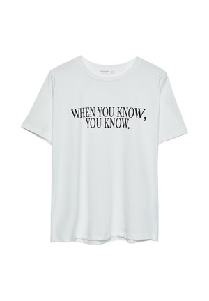 T-shirt en coton blanc à manches courtes et col rond. Dispose d'un texte noir : "QUAND VOUS SAVEZ, VOUS SAVEZ." Imprimé en gras.