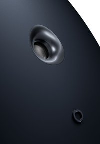 Enceinte noire mate au design arrondi. Présente un port circulaire et une zone de grille texturée. Des lignes simples et épurées soulignent l'esthétique moderne.