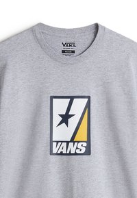 Šedé bavlněné tričko s velkým černým, žlutým a bílým logem Vans s designem hvězdy. Klasický střih s kulatým výstřihem.