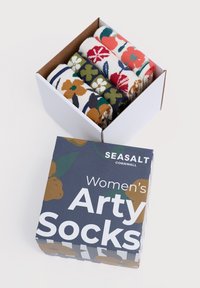 Cinque paia di calzini a righe con motivo floreale all'interno di una scatola bianca, con un'imballaggio decorativo "Calzini Arty da Donna" di Seasalt Cornwall nelle vicinanze.