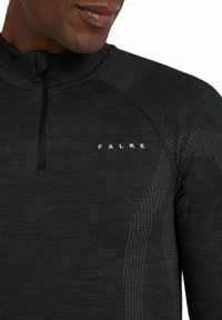 Czarna koszula z długim rękawem i półzamkiem przy kołnierzu, z prążkowaną fakturą i subtelnymi paskowanymi wzorami. Logo "FALKE" w białym kolorze na piersi.