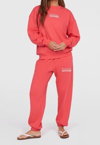 Felpa corallo e jogger coordinati, in misto cotone, con polsini e vita a coste, riportante la scritta "The Future Surf Society" in bianco.