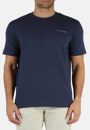 Camiseta de algodón azul marino con mangas cortas, cuello redondo y detalle de logotipo blanco en el lado izquierdo del pecho. Textura suave y corte regular.