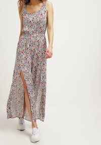 Maxi šaty s květinovým vzorem, s přiléhavým živůtkem, elastickým pasem a vysokým rozparkem na stehno. Vyrobené z lehké látky s vícebarevným květinovým motivem.