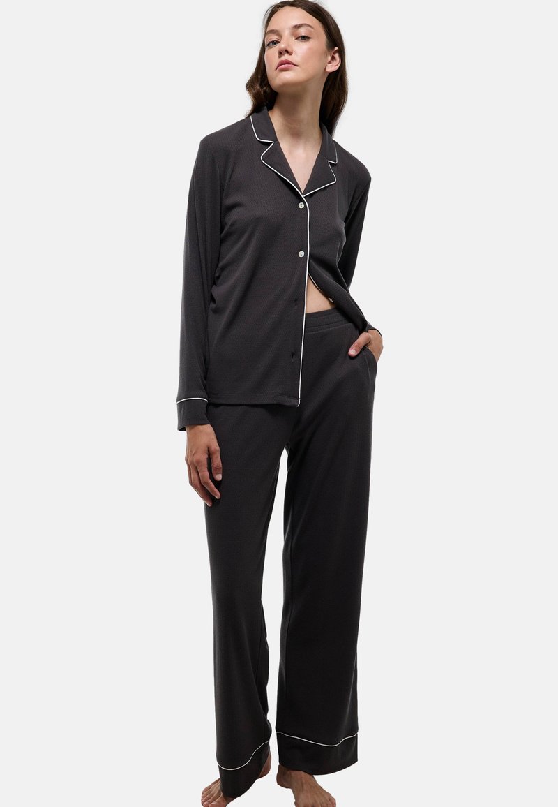 Ensemble de pyjama gris foncé en tissu doux. Haut à manches longues avec boutons et passepoils blancs, accompagné d'un pantalon assorti, offrant une coupe décontractée et des poignets larges.