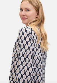 Bluzka z długim rękawem w kolorze granatowym z kremowo-beżowym wzorem paisley, charakteryzująca się gładką fakturą materiału i luźnym krojem.