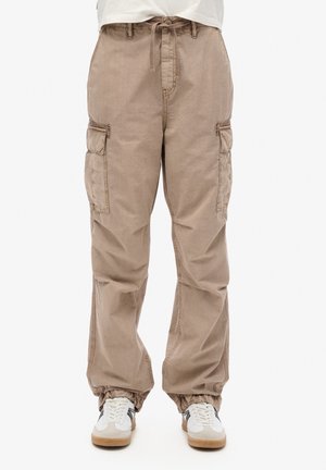 Beige cargo bukser med snor i taljen, elastiske manchetter og flere lommer på siderne, lavet af blødt bomuldsstof.