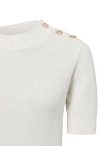 Witte gebreide top met korte mouwen en een ribbelstructuur, voorzien van een ronde hals en drie knopen in goudkleur op de schouder.